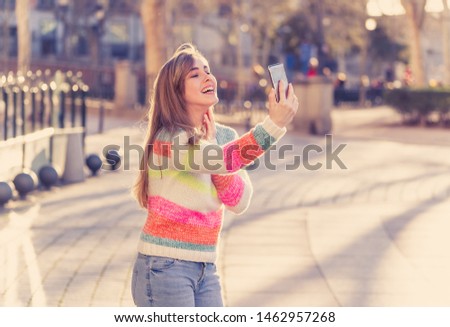 Pretty teenager girl taking selfie happy and excited in the city. Young student woman recording video of herself blogging outdoors In Millennial generation Connections Technology and Online trends.