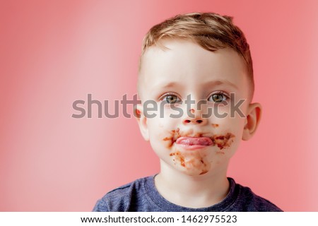 Little boy eating donut chocolate. Cute happy boy smeared with chocolate around his mouth. Child concept Royalty-Free Stock Photo #1462975523