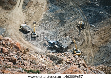 Excavator loading dumper truck on mining site stock photo