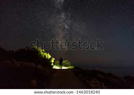 Beautiful nature and landscape photo of dark night in Razanj Croatia. Nice sky with stars at the Adriatic Sea. Man walking outdoor with flashlight. Calm, peaceful outdoors image.
