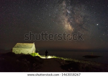 Beautiful nature and landscape photo of dark night in Razanj Croatia. Nice sky with stars at the Adriatic Sea. Man walking outdoor with flashlight. Calm, peaceful outdoors image.
