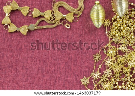 Background in the form of two Christmas tree garlands of toys and golden decorations on a burgundy background above and to the right, below - an empty place