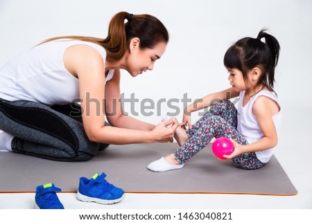 Young asian mother helping her lovely daughter wearing sport shoes before exercise on white background