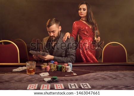 Charming wealthy couple are playing poker at a casino.