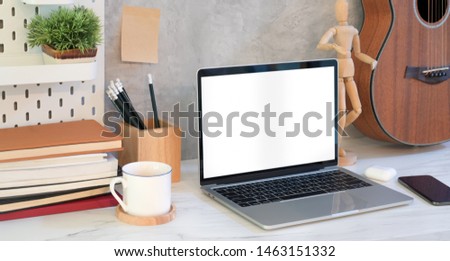 Comfortable workplace with open blank screen laptop and office supplies 
