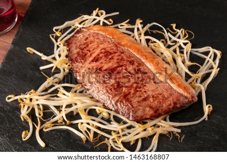 Kobe meat, wagyu beef steak, seared, with soy sprouts, on a black plate