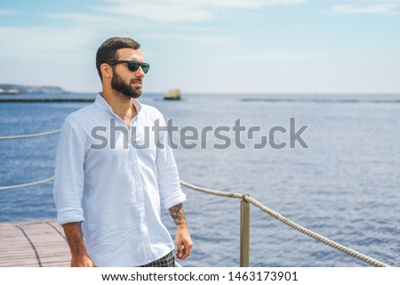 Stylish guy in a white shirt on the background of the sea Royalty-Free Stock Photo #1463173901