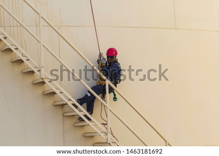 Male worker rope access height safety inspection of thickness stairway storage oil and gas tank