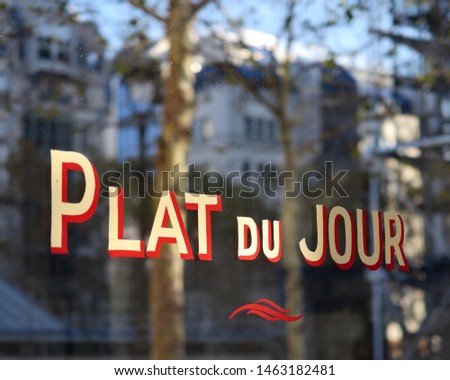 French text: Plat du jour. English translation: dish of the day. Painted inscription on the facade of a restaurant, Paris, France.