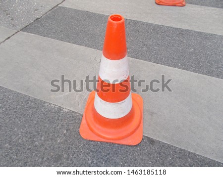 
Traffic cone with orange and white stripes.					