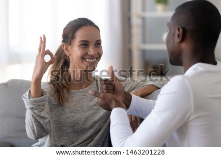 Happy mixed race deaf couple using sign language for communication at home sit on sofa, interracial hearing impaired disabled man and woman showing hand gestures as finger speech concept Royalty-Free Stock Photo #1463201228