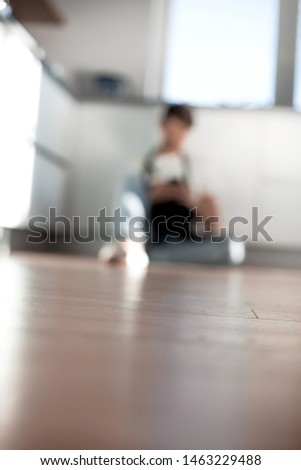 blurred image of a man with a smartphone in the home kitchen