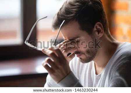 Close up of tired male take off glasses massage eyes feel fatigue suffering from strong headache, exhausted unwell man having eyestrain or astigmatism overwhelmed with work. Health problem concept Royalty-Free Stock Photo #1463230244