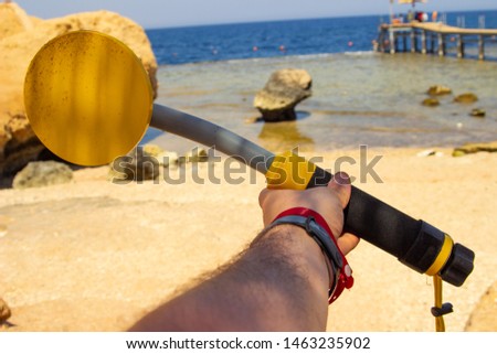The photo of an underwater metal detector in a hand. Treasure searching and tourist adventure background.