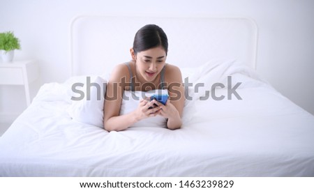 Holiday concept. A young woman is playing a mobile phone in the bedroom.