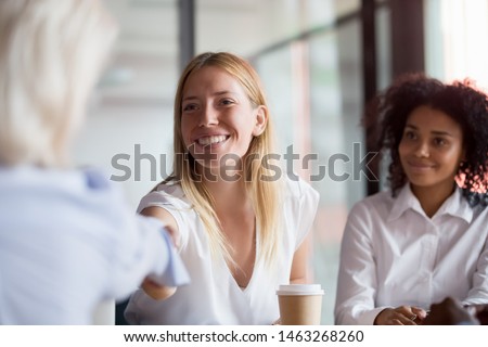 Smiling Caucasian female employee shake hand of colleague greeting get acquainted at company office meeting, positive businesswoman handshake business partner introducing or closing deal Royalty-Free Stock Photo #1463268260