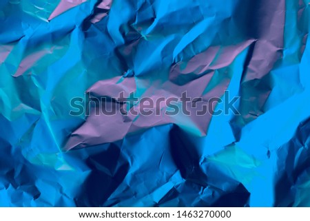 Crushed paper background in vibrant bold gradient holographic neon colors.  Flat lay. Top view.