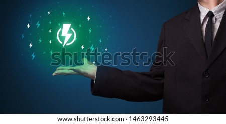 Hand in suit holding lightning bolt on his hand, green environment concept