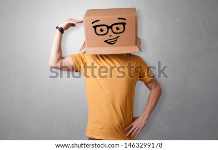 Handsome man standing and gesturing with a carton box on his head