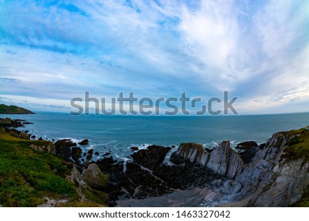 Sharp dangerous rocks in north Devon coast in a ultra wide angle view with beautiful sky