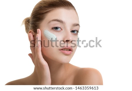 Young woman applying face cream or facial mask at her face. Beauty model with perfect fresh skin and long eyelashes cares about her skin at home. Spa and Wellness, Skin Care Concept.  Royalty-Free Stock Photo #1463359613