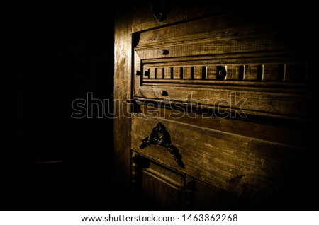 Close up view of old antique wooden door inside a dark room. Selective focus. Horror concept