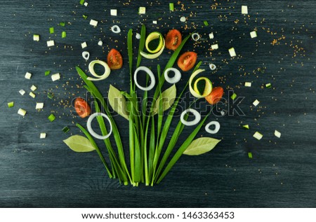 BOW ON THE BACKGROUND. GREEN BOW OF THE ONIONS, WHITE ONIONS AND TOMATO ON A STRONG WOODEN SURFACE. CONCEPT VEGETABLE PICTURE. VIEW FROM ABOVE. COPY SPACE