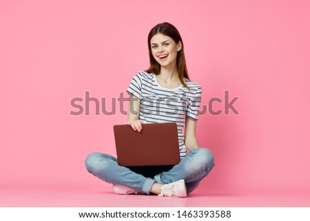 woman with laptop on a pink background