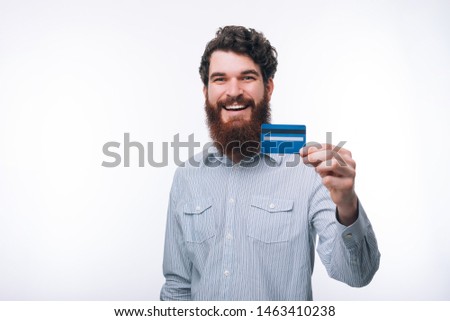 Photo of smiling man with beard in casual showing blue credit card