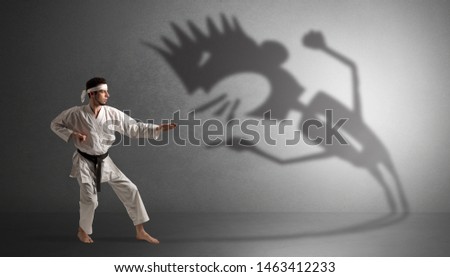 Young karate man fighting with a big black scary shadow
