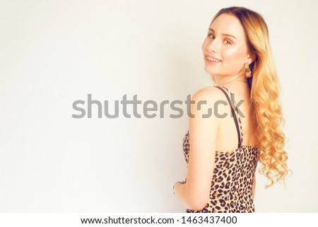 Portrait of a beautiful blonde with long hair. Girl with gold earrings, costume jewelry, dress with leopard print. Young girl with braces, plate, perfect teeth. Fashion girl in leopard with braces. 