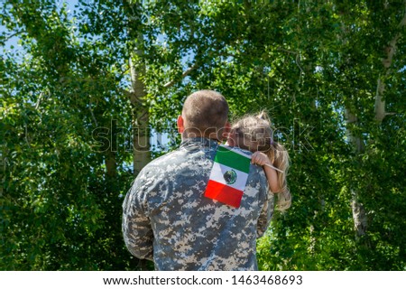 Happy reunion of soldier from Mexico with family, daughter hug father. A little girl holds the flag of Mexico in her hand