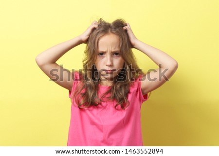 The girl is scratching her head on a colored background.
