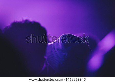 Festival crowd in purple lights with bucket hat at night