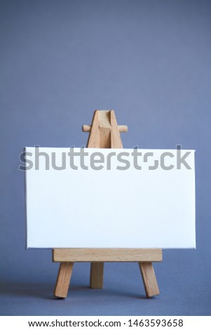 Miniature easel with a white board for writing, pointer on white surface, concept of direction and graphics, selective focus