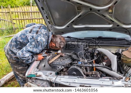 A car mechanic repairs an old car, performs welding and locksmith work to restore the body geometry, a profession for real men who value their skills and work for money with full dedication.