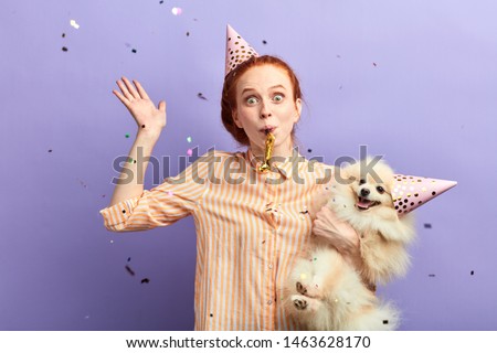 excited ginger girl has positive time at party. close up portrat, isolated blue background, studio shot