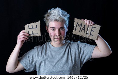 Handsome transgender teenager tearing the word Female into MALE in Gender identity, equality and human rights. Breaking silence about own gender identity transgender Pride and freedom concept. Royalty-Free Stock Photo #1463712725