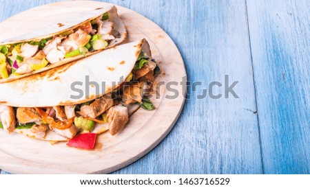 Tacos with vegetables, avocado and chicken breast on a wooden round board - traditional mexican appetizer
