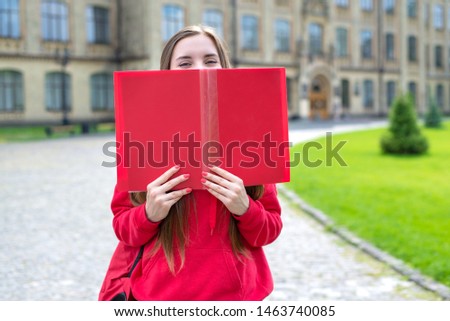 Photo portrait of charming beautiful cheerful excited teen hipster millennial closing covering her face and smile with big open book