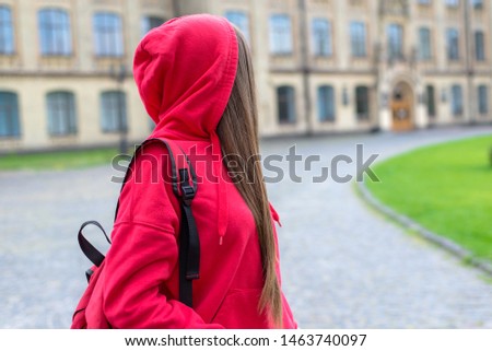 Side profile photo of sad unhappy sad regretful teen teenager hipster person looking back at university building