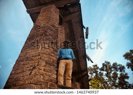 Man wearing blue shirt standing under an old bridge unique photo