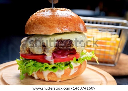 American fast food. Juicy American cheeseburger with beef cutlets, sauce and tomato on a black background.