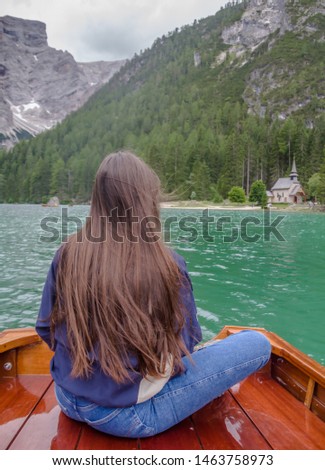 Young female tourist sitting in a wooden rowing boat enjoying the amazing nature view of Lake Braies (Italian: Lago di raies, German: Pragser Wildsee). Dolomites Mountains, South Tirol, Italy, Europe