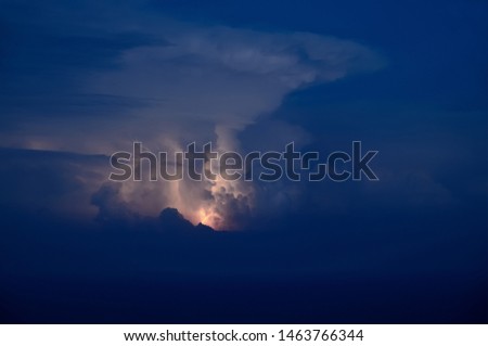 lightning shines in the clouds above the sea at night