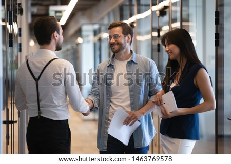 Friendly male professional colleagues greeting handshaking meeting in company office hall, smiling businessmen shaking hands starting teamwork partnership standing in corporate work space hallway Royalty-Free Stock Photo #1463769578