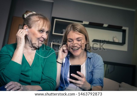 Happy senior woman and her daughter listening to music together.