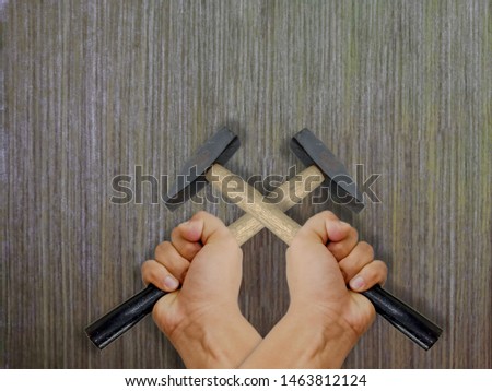 Both hands holding a hammer, pounding punctuate Wooden floor backdrop.