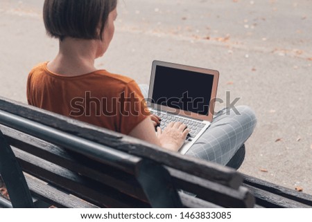 Woman using laptop computer on street bench, mock up screen, selective focus image