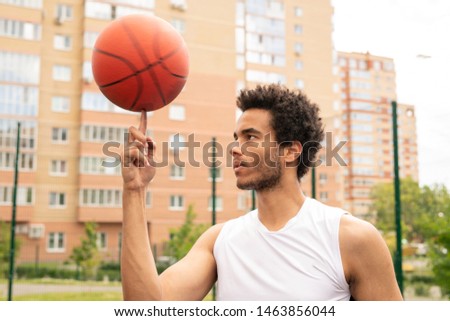Young active professional basketball player holding rotating ball on forefinger Royalty-Free Stock Photo #1463856044